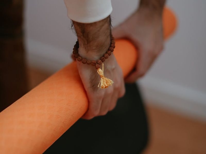 Detail shot of hands resting on a yoga mat during meditation.